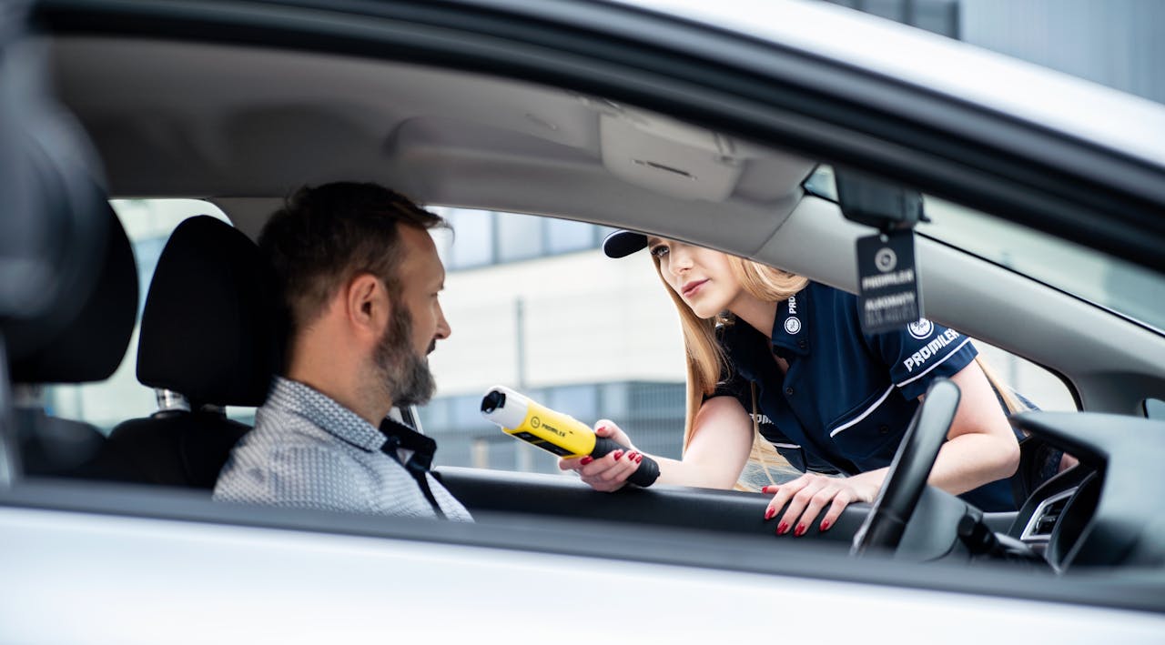 services-02 A police officer conducts a breathalyzer test on a male driver during a road safety check.